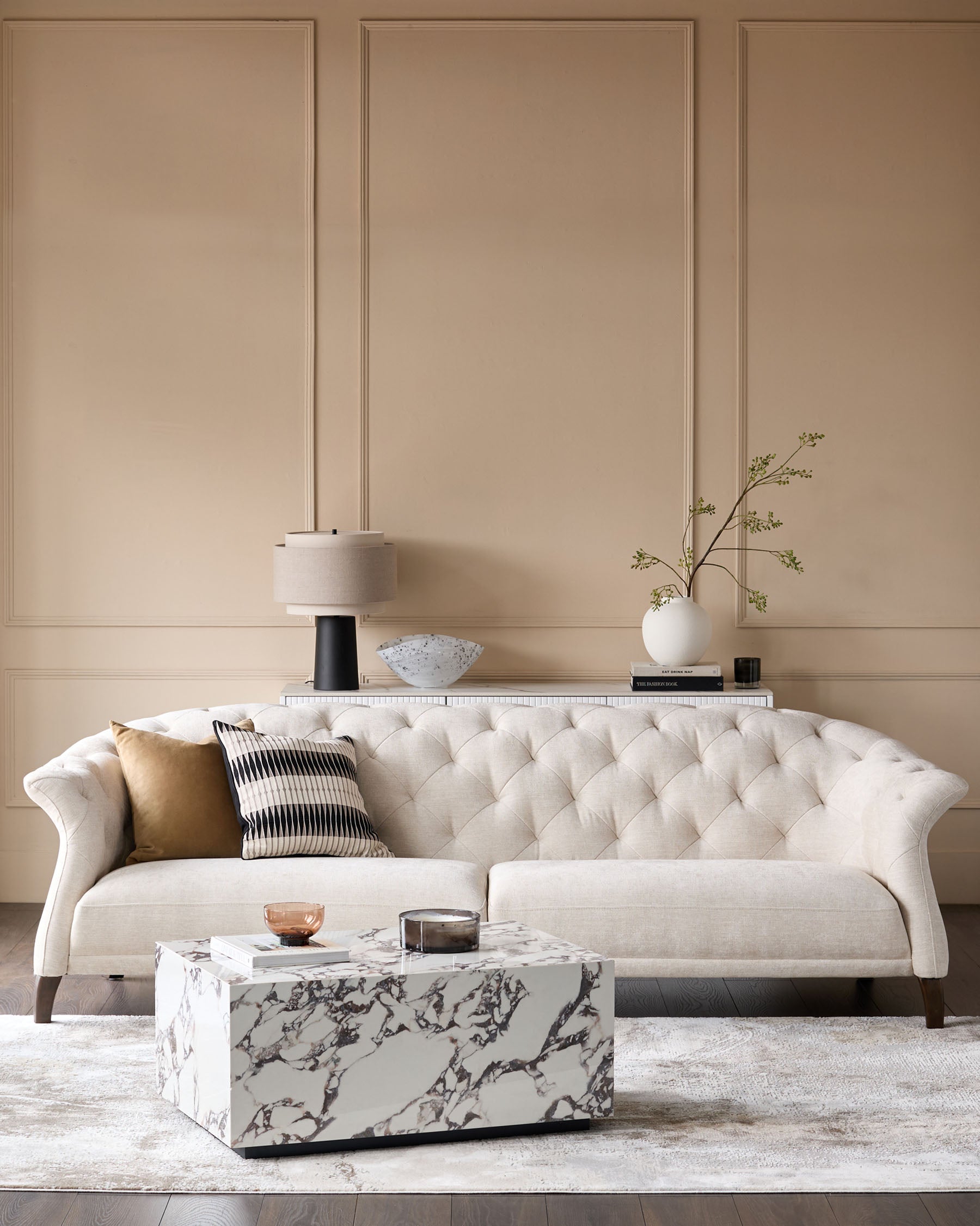 Stylish living room featuring a buttoned sofa, marble coffee table and elegant wall panelling.