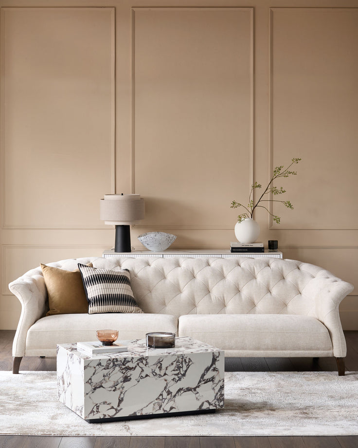 Stylish living room featuring a buttoned sofa, marble coffee table and elegant wall panelling.
