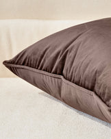 Large chocolate brown cushion with soft texture, displayed at an angle on a neutral beige surface.