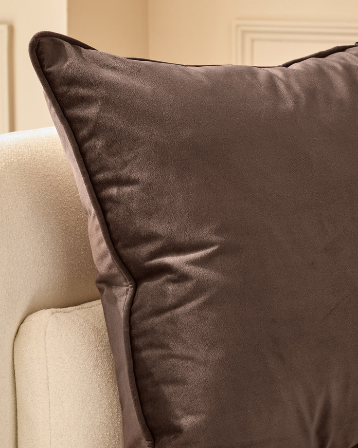 Luca cushion in chocolate brown, large size, displayed on cream-colored furniture showing texture and piping detail.