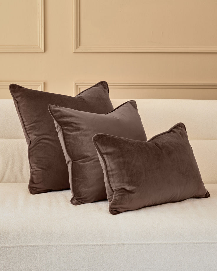 Luca Rectangle Cushion in Chocolate displayed on cream sofa, shown in set of three varying sizes.