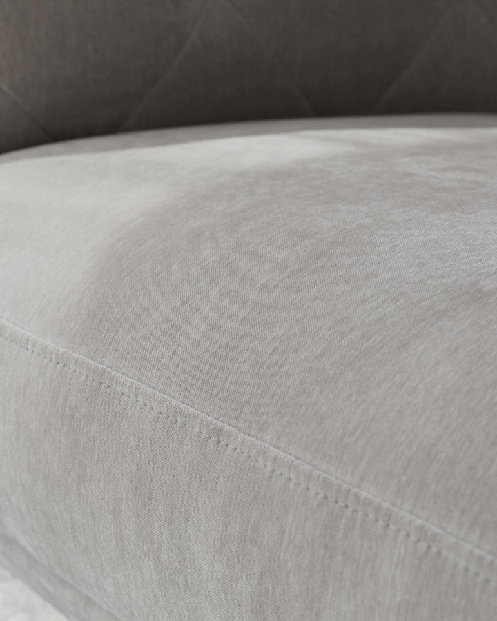 Close-up of a grey cushioned sofa with visible stitching detail, suggesting quality craftsmanship and comfort.