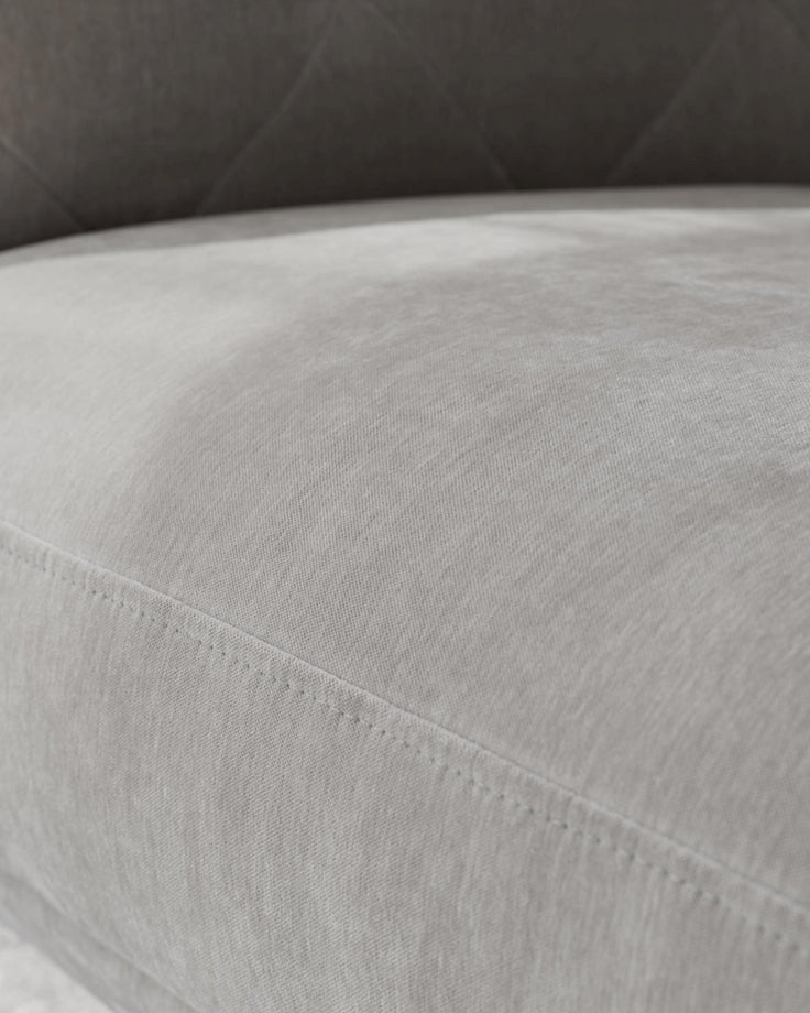 Close-up of a grey cushioned sofa with visible stitching detail, suggesting quality craftsmanship and comfort.