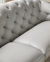 A close-up of a grey leather, buttoned sofa with a large cushion. Elegant and sophisticated, ideal for a stylish living room.