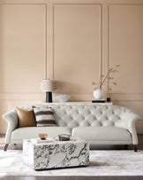 Elegant sofa with tufted details, marble coffee table, console table, lamp, cushions and other stylish decor items.