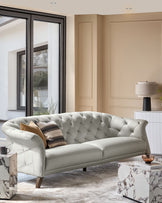 A grey, button-backed sofa takes centre stage, complemented by marble side tables and a neutral colour scheme.