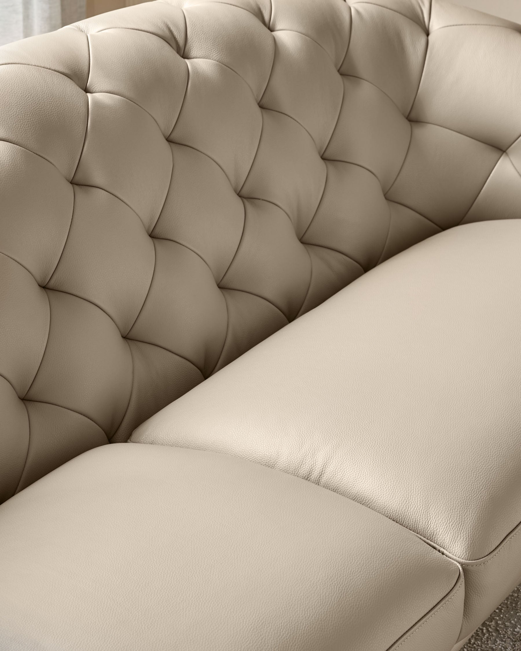 Close-up of a luxurious, button-tufted, beige leather sofa. Perfect for a sophisticated living space.