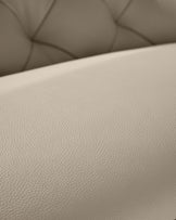 Close-up of beige, button-backed leather furniture. The focus is on the material's texture.