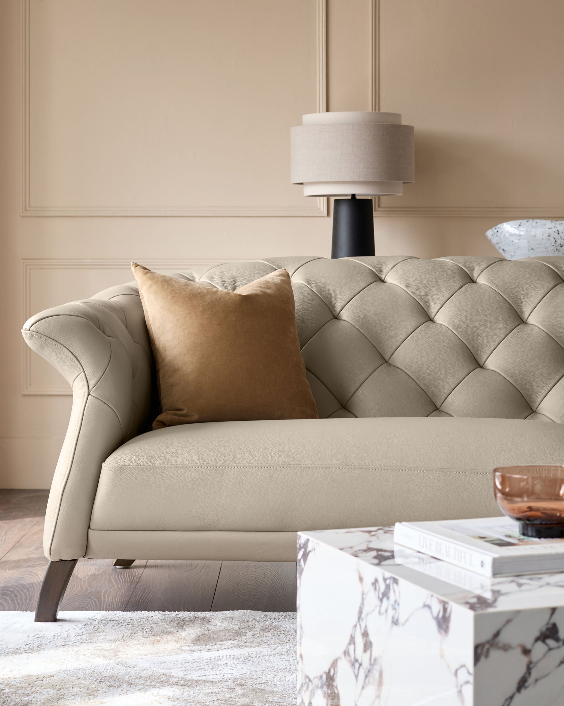 Elegant cream leather sofa with button-tufted back and a modern marble side table, creating a luxurious living space.