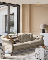 A beige, button-back sofa sits in a living room, with marble tables and a neutral colour scheme creating a luxurious atmosphere.