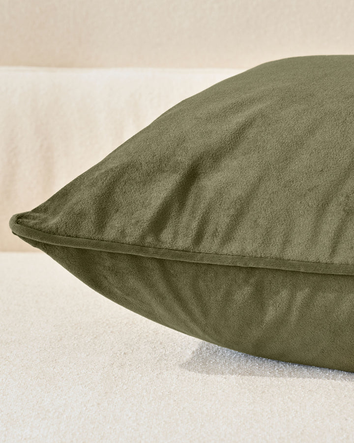 Luca medium cushion in olive green, shown at an angle highlighting its plump shape and soft texture against a neutral background.