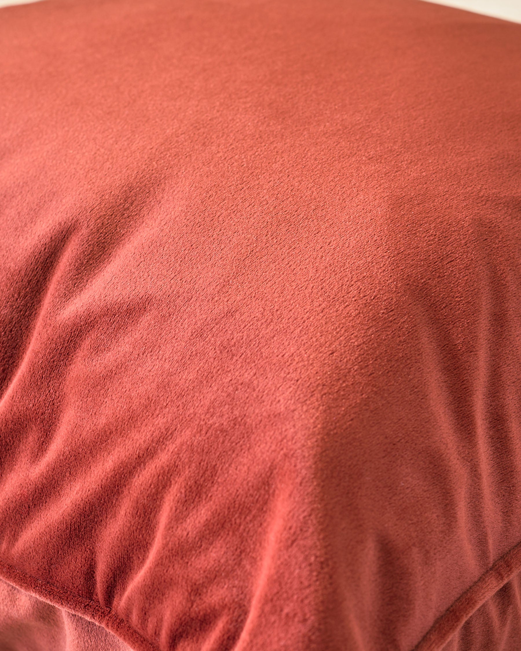 Luca rectangular cushion in toffee red, close-up showing soft fabric texture and subtle folds.