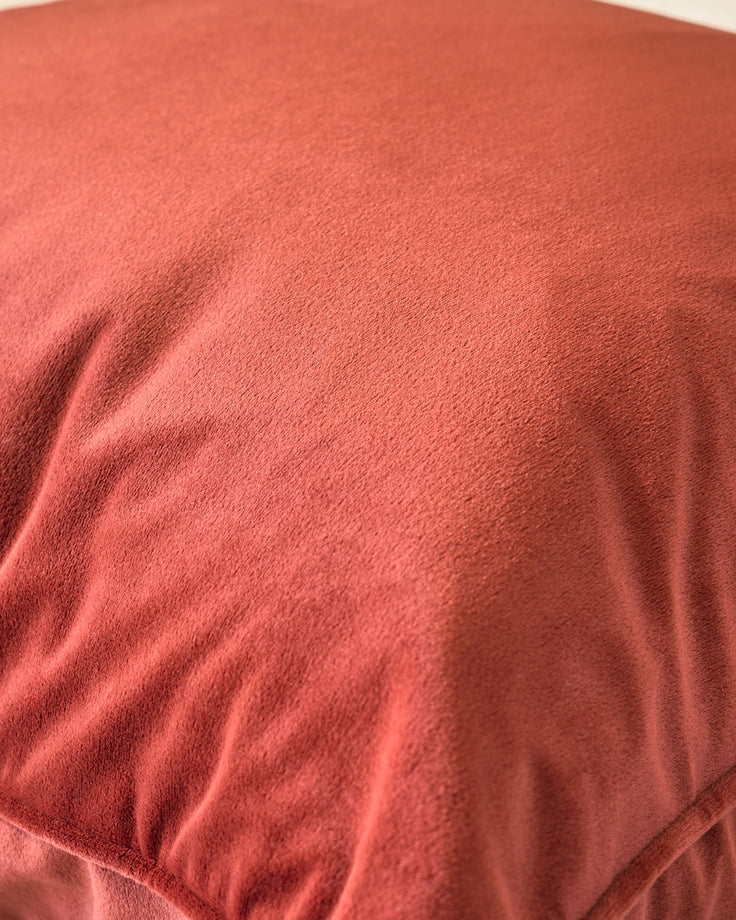 Luca rectangular cushion in toffee red, close-up showing soft fabric texture and subtle folds.