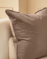 Large mink velvet cushion with piping detail, displayed on a cream upholstered chair.