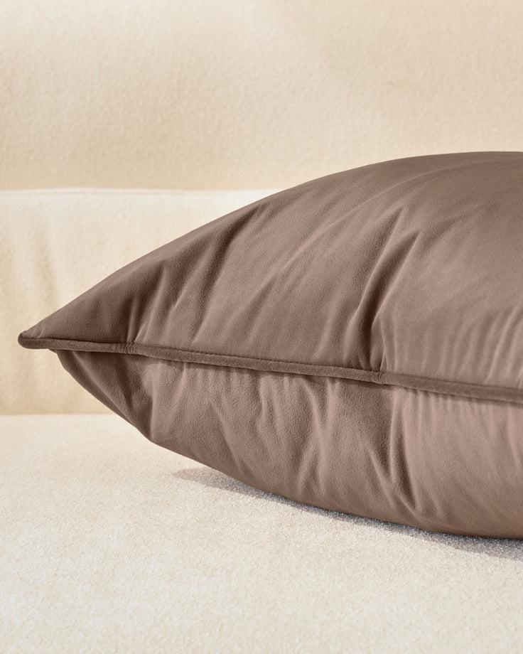 Mink-colored rectangular Luca cushion displayed at an angle, showing its plump form and neat seam detail against a neutral background.