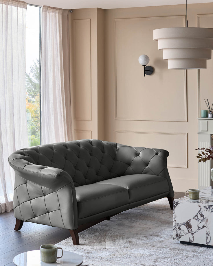 A grey leather sofa with buttoned detailing sits on a patterned rug in a room with neutral tones.