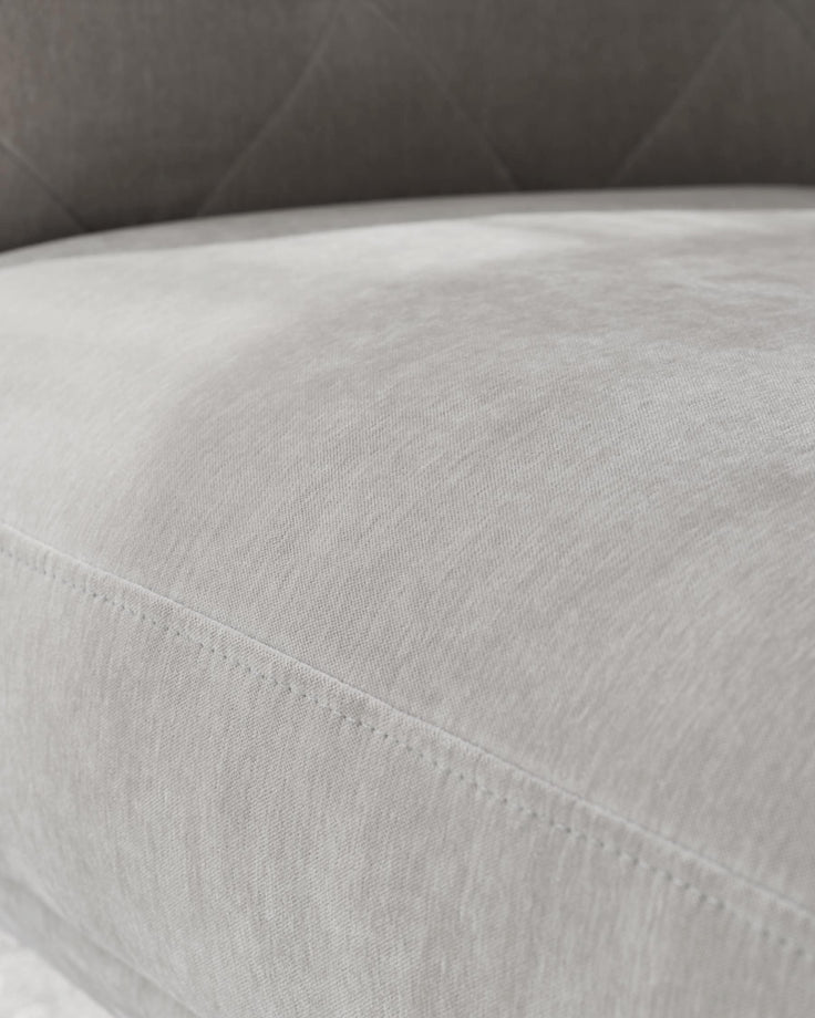 Close-up of a light grey sofa, showcasing the fabric and stitching detail.