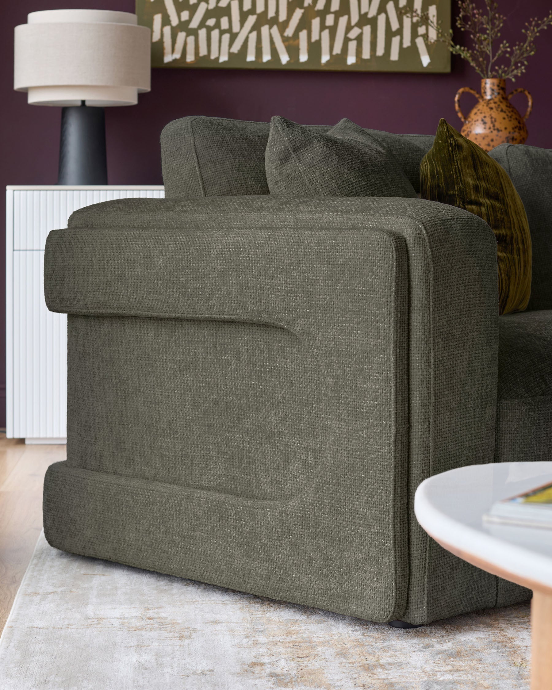 Lynetta 3-seater sofa in dark green weave fabric, shown from side angle in styled living room setting.