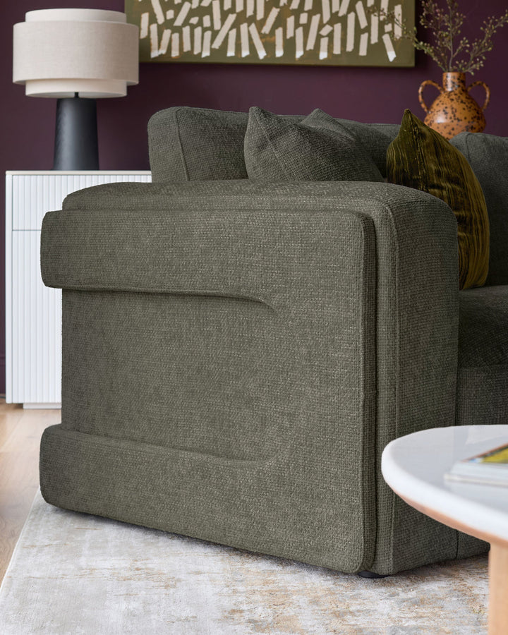 Lynetta 3-seater sofa in dark green weave fabric, shown from side angle in styled living room setting.