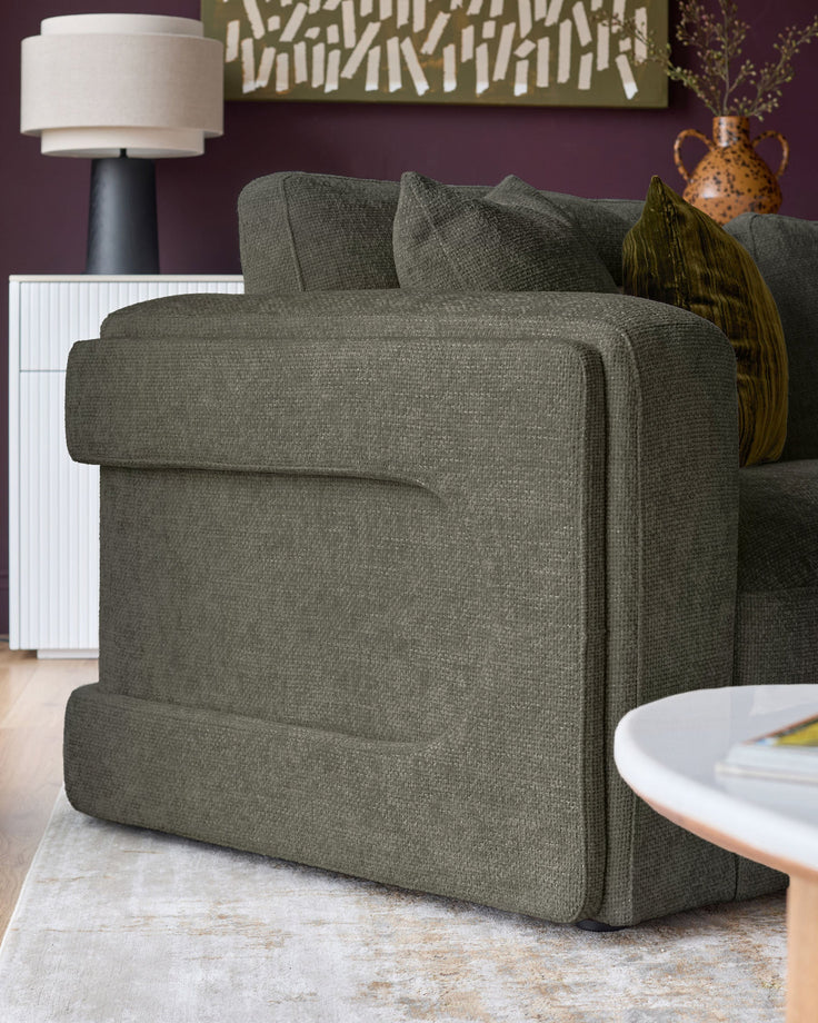 Lynetta 3-seater sofa in dark green weave fabric, shown from side angle in styled living room setting.