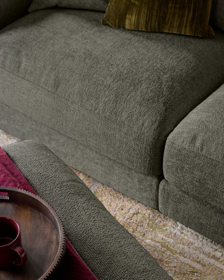 Lynetta 3-seater sofa in dark green weave fabric, shown from side angle with footstool and cushions visible.