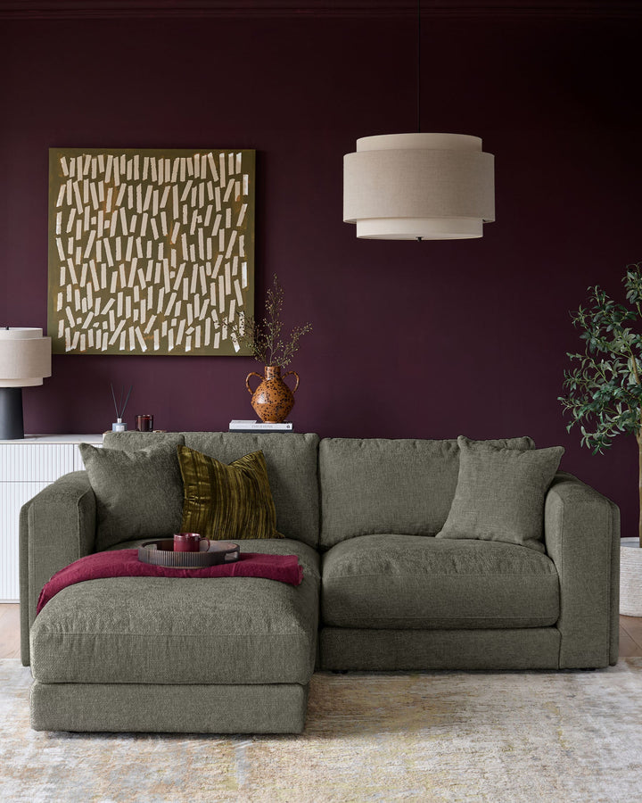 Lynetta 3-seater sofa with footstool in dark green weave fabric, displayed in a living room setting.