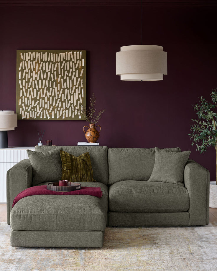 Lynetta 3-seater sofa with footstool in dark green weave fabric, displayed in a living room setting.