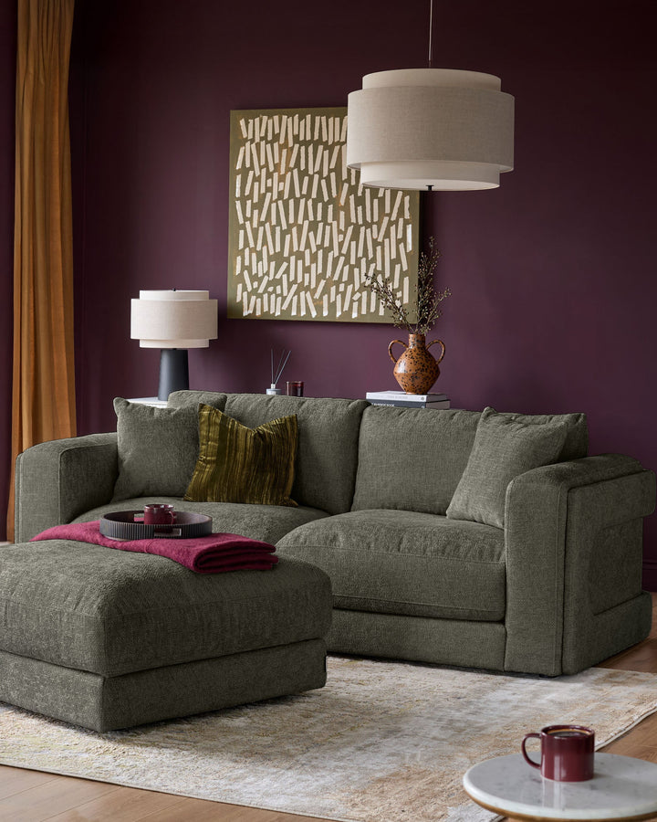 Lynetta 3-seater sofa with footstool in dark green weave fabric, shown in a styled living room setting.