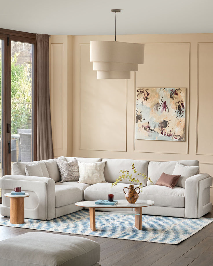 Lynetta small corner sofa in natural grey weave fabric, styled in a bright living room with wood accents and neutral décor.