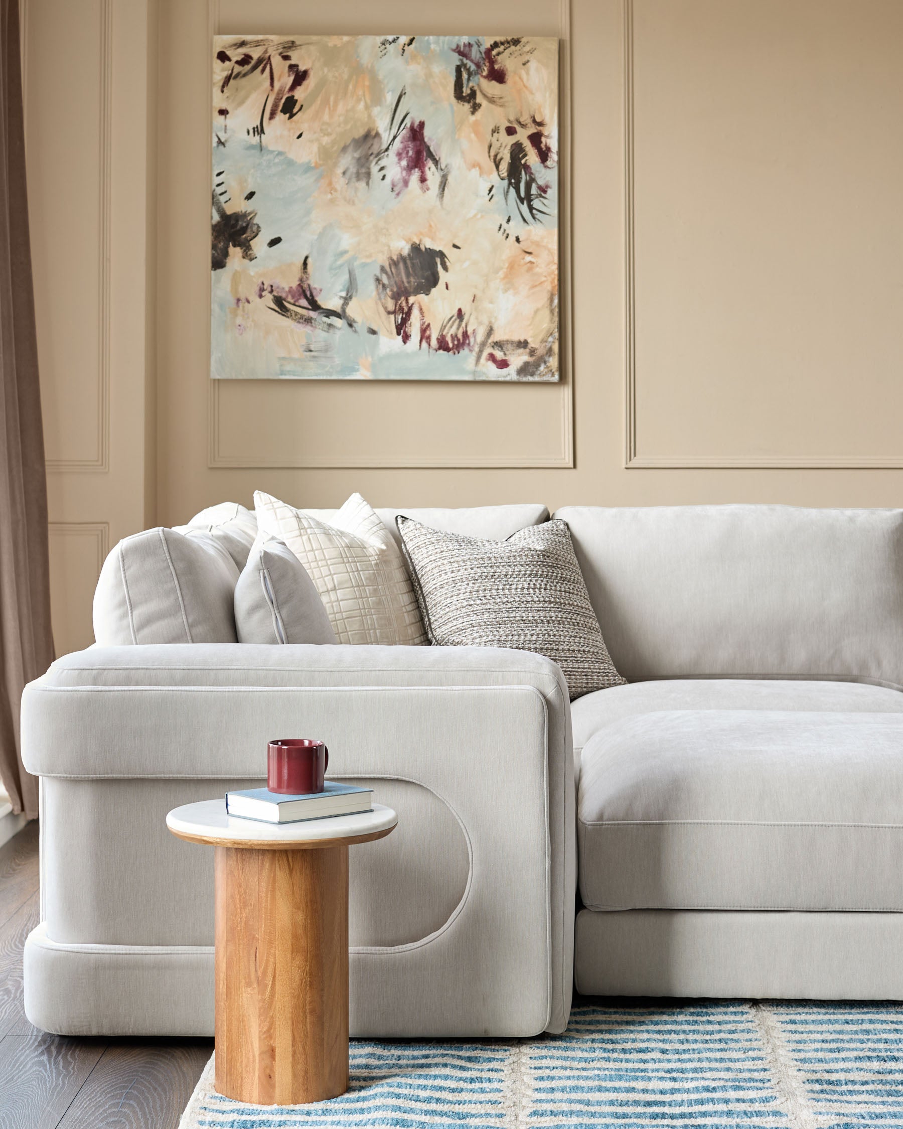 Lynetta small corner sofa in natural grey weave fabric with matching footstool, styled with cushions in a contemporary living room setting.