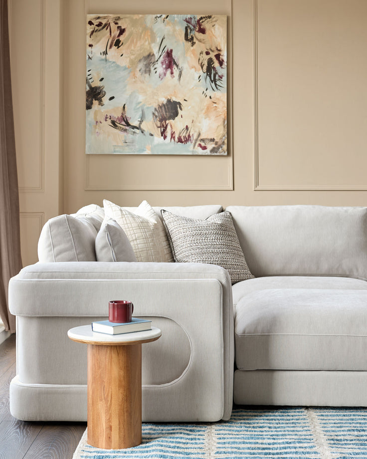 Lynetta small corner sofa in natural grey weave fabric with matching footstool, styled with cushions in a contemporary living room setting.