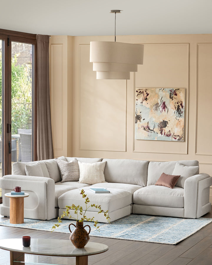 Lynetta small corner sofa with footstool in natural grey weave fabric, displayed in a contemporary living room setting.