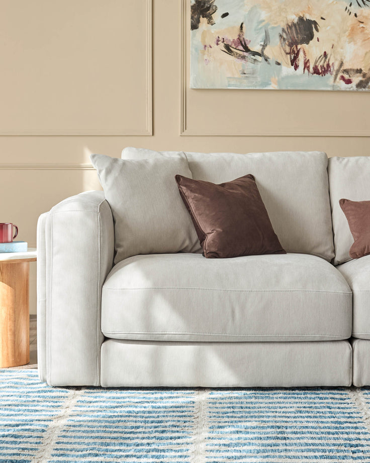 Lynetta 3-seater sofa in natural grey weave fabric with brown velvet cushions, shown in a living room setting.
