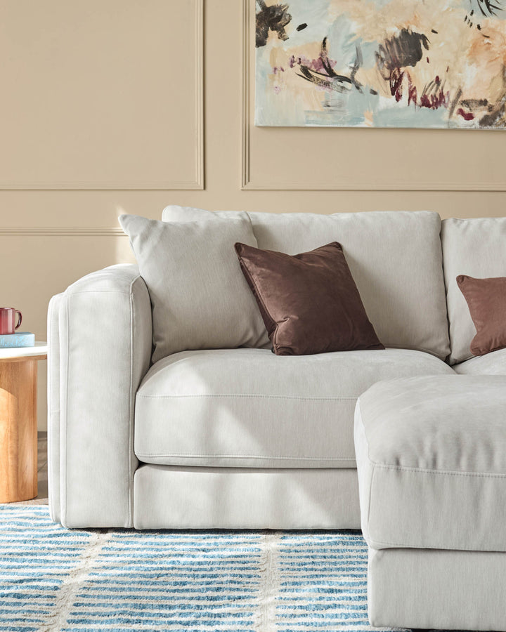 Lynetta 3-seater sofa with footstool in natural grey weave fabric, styled with brown accent pillows in a neutral room setting.