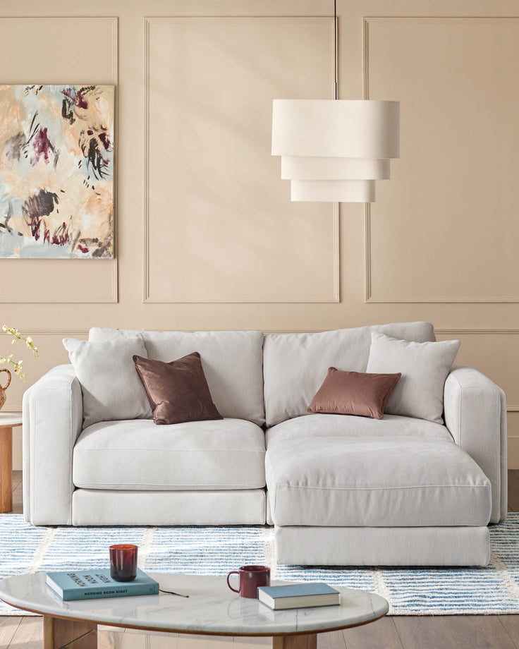 Lynetta 3-seater sofa with footstool in natural grey weave fabric, styled in a neutral living room with decorative pillows.
