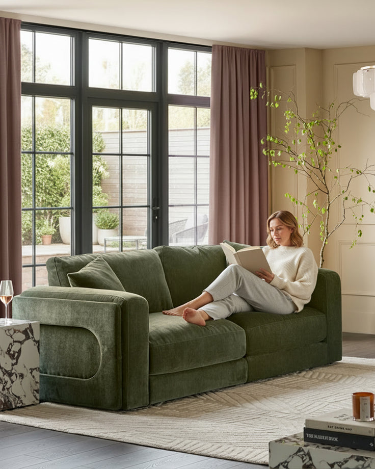 Lynetta 3-seater sofa in dark green weave fabric, displayed in a bright living room with woman reading on seat.