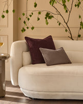 Mink rectangular cushion displayed on a cream curved sofa in a styled living room setting.