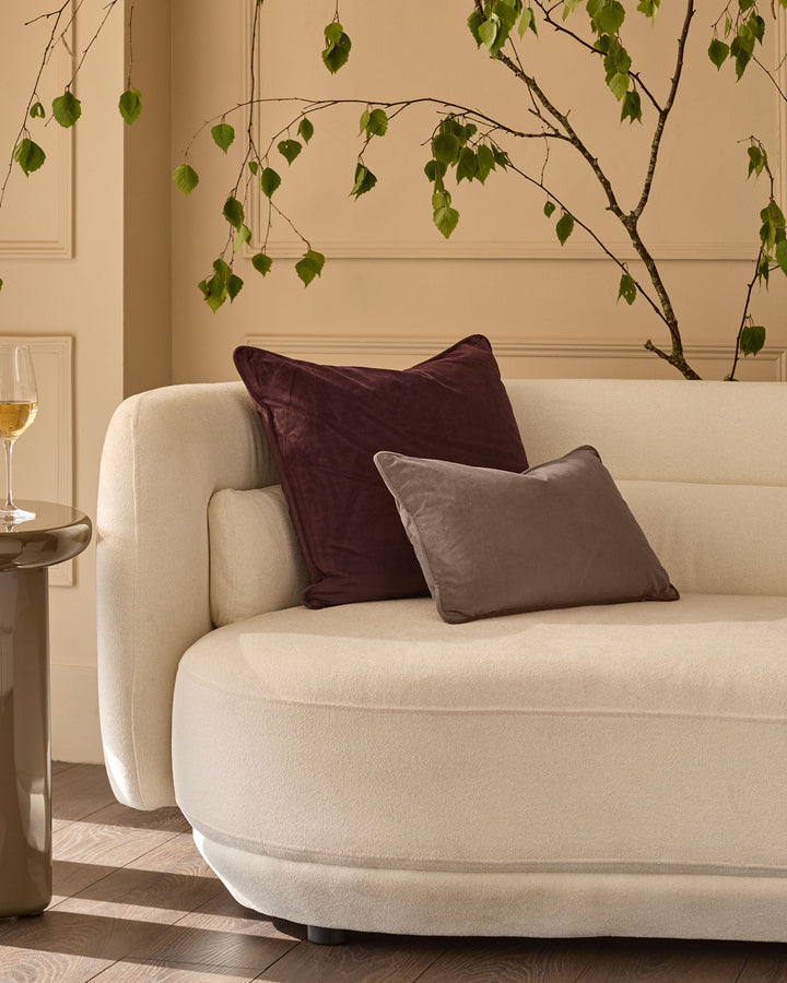 Mink rectangular cushion displayed on a cream curved sofa in a styled living room setting.