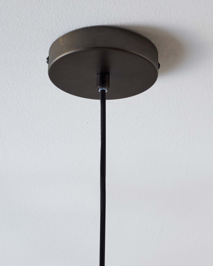 A ceiling light with a dark metal canopy and a black cord, providing a minimalist and modern lighting solution.