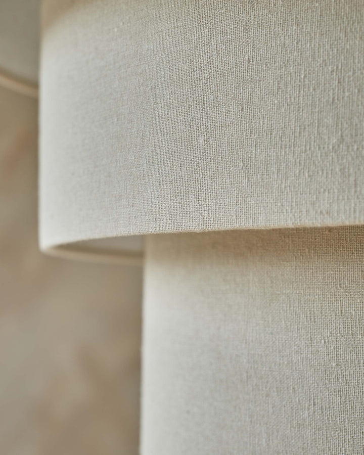 Close-up of a tiered lampshade featuring a neutral-toned woven linen texture.