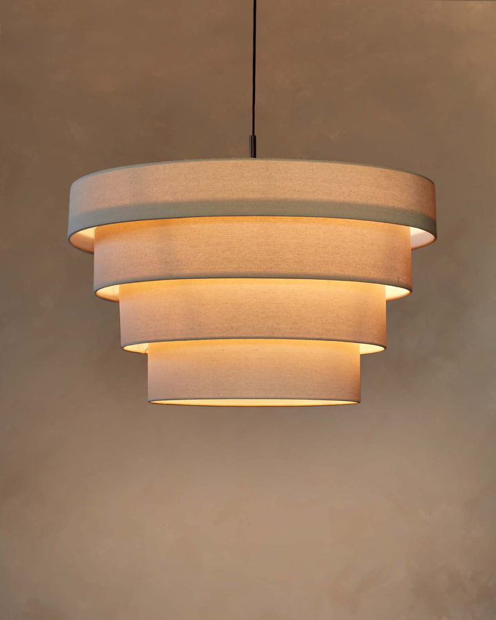 A four-tiered, drum-shaped, fabric pendant light hangs from the ceiling, casting a warm, inviting glow.