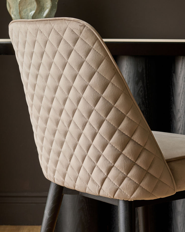 Mae Velvet Dining Chair in Champagne - side view showing quilted diamond pattern backrest and dark wooden legs.