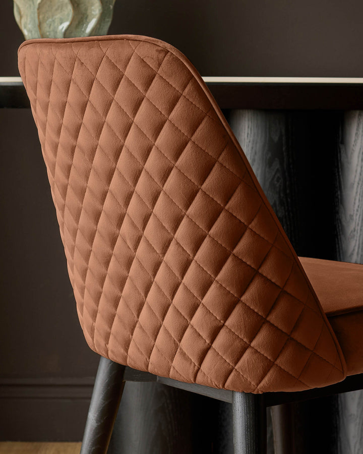 Mae velvet dining chair in rust, shown from behind displaying quilted diamond pattern backrest and dark metal legs.