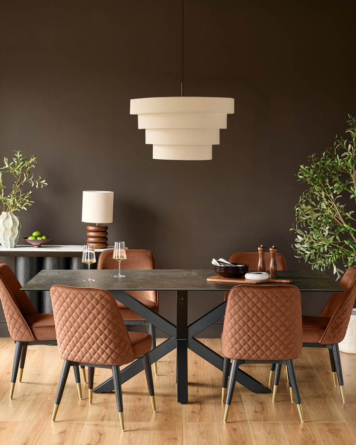 Mae velvet dining chair in rust, featuring quilted backrest and black legs with brass foot caps, shown in dining room setting.