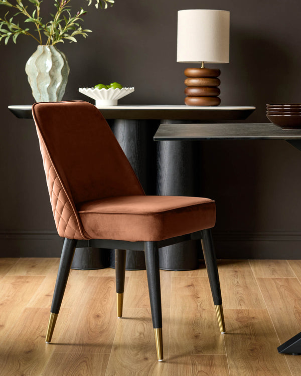 Mae rust velvet dining chair with quilted backrest and black wooden legs with brass feet.