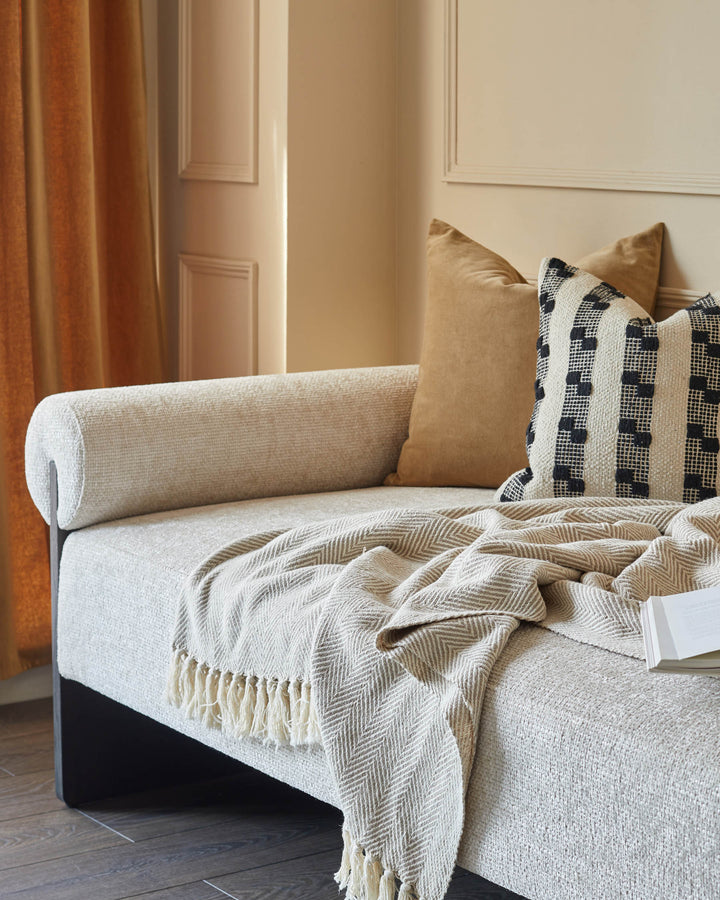 A daybed with neutral upholstery, cushions and a throw. Modern design with clean lines. Perfect for a living room.