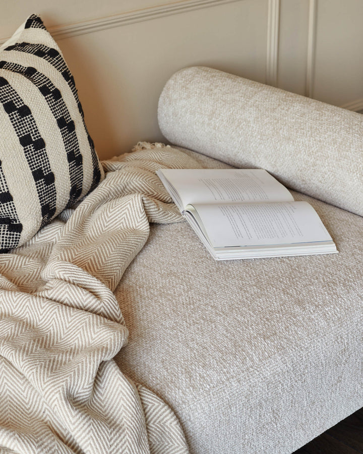 Stylish sofa with monochrome cushion, textured bolster and a patterned throw, topped with an open book.