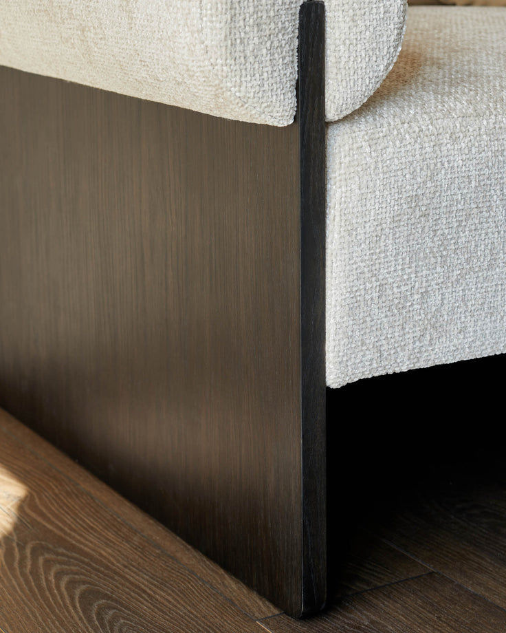 Close-up of a cream fabric sofa with a dark wood frame, showcasing texture and design.