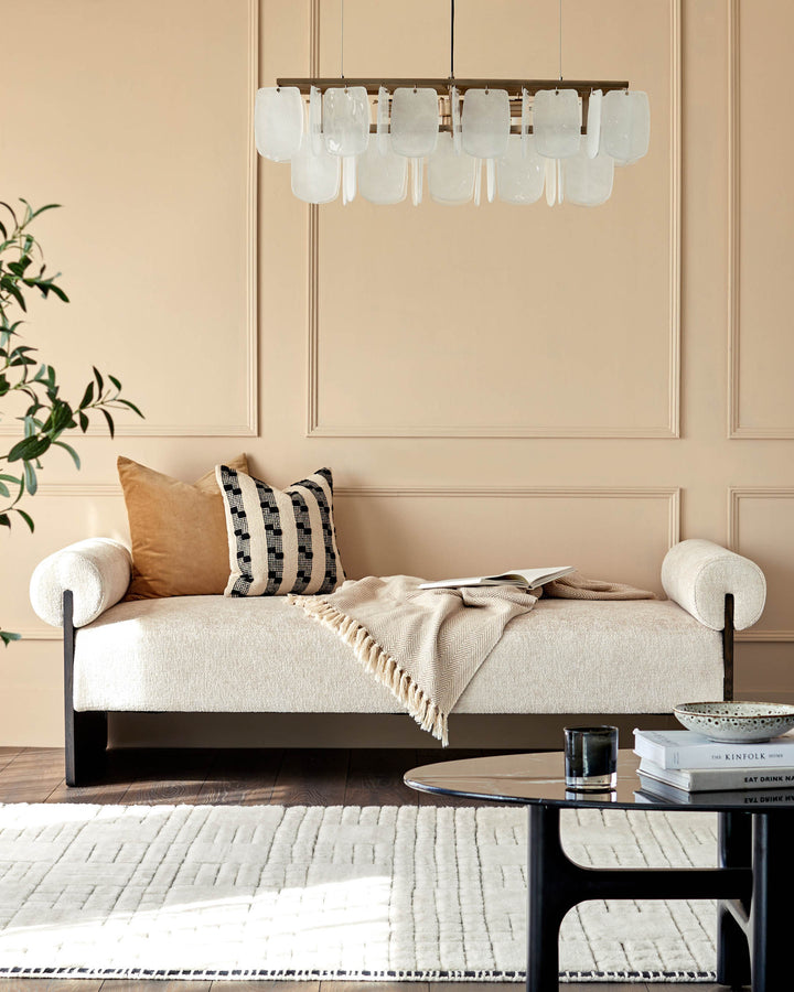 Stylish living room with modern sofa, coffee table, patterned rug, and lighting fixture.