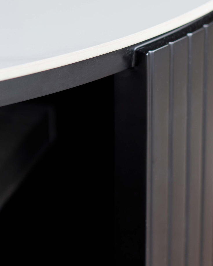 Close-up of black handle detail on Malachy coffee table with white ceramic top and ribbed black base.